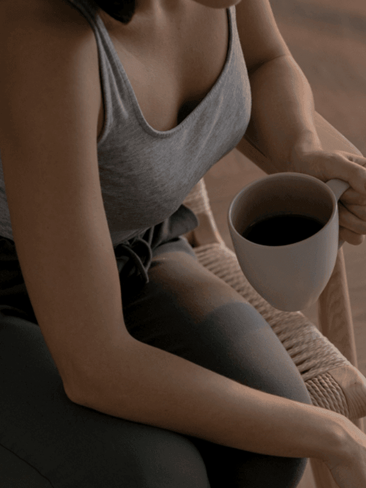 Người phụ nữ ngồi cầm cốc, trở lại nhịp sống thường ngày sau buổi tầm soát